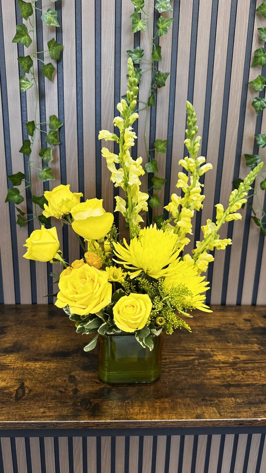 Before: yellow roses and snapdragons in a cube vase, photographed in the shop